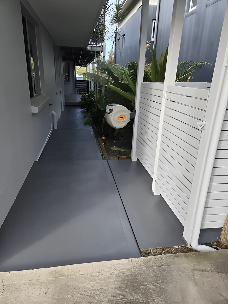 A charcoal coated concrete side path